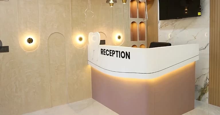 Reception desk at V-Dent Dental Care, with warm wall lighting and a marble finish, New Nikol, Ahmedabad